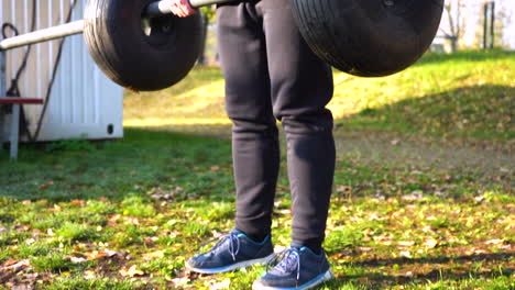 guy doing deadlift with a metal bar and tires in a park,autumn,czechia