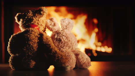 two friends a rabbit and a bear bask near the fireplace hugging - friendship and comfort in the hous