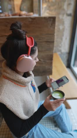 woman enjoying matcha tea and using phone in a cafe