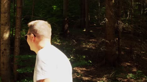 Man-In-Sunglasses-Smiling-While-Walking-In-The-Forest-Near-Lake-Sfanta-Ana-In-Romania