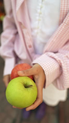 child holding apples and peaches