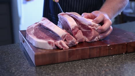 butcher cutting and slicing a pork meat using a stainless knife on the kitchen