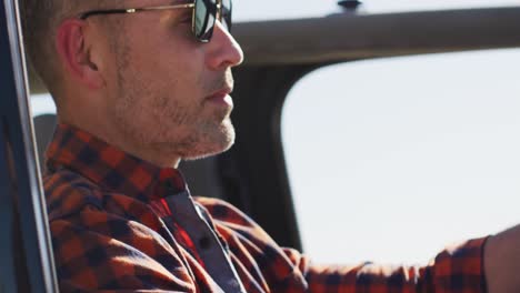 Caucasian-man-wearing-sunglasses-sitting-in-car-driving-on-sunny-day