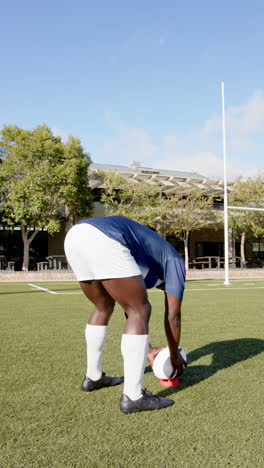 vertical video: athlete preparing to kick rugby ball on sunny outdoor field