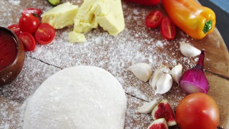 rodillo con masa de pizza, harina, verduras y especias en el plato