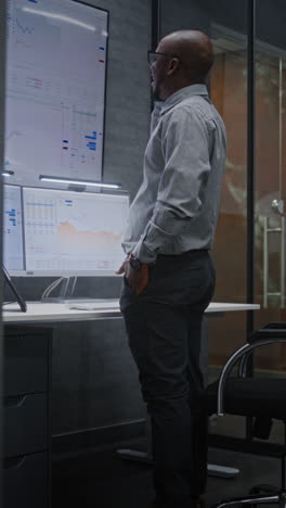 advanced trading office: excited financial analyst having phone call, celebrating profitable investments. african american businessman happy about successful financial deal or contract. vertical shot.