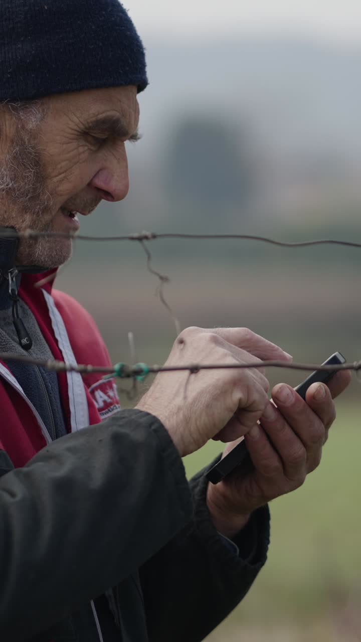 Man using a phone outdoors by barbed wire