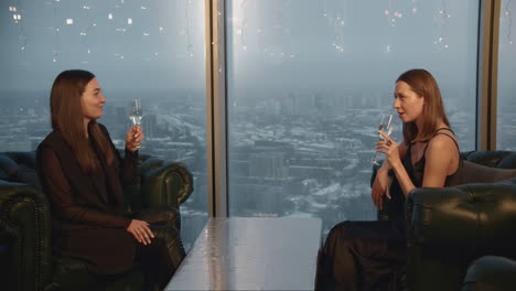 two women celebrating with champagne in a high-rise restaurant