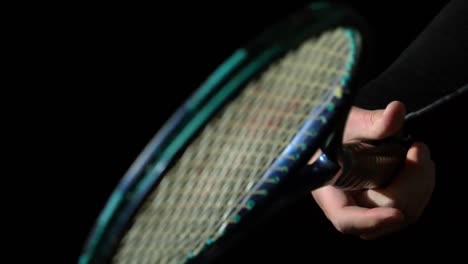 Hand-spinning-a-tennis-racket-on-black-background