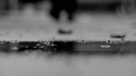 Low-angle-view-of-an-unrecognizable-person-walking-through-a-wet-street-during-a-rainy-day,-blurry-background