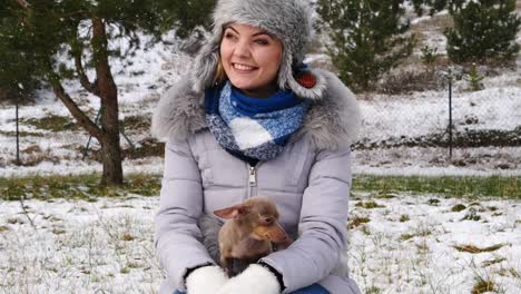 mujer jugando con su pequeño perro fuera del invierno