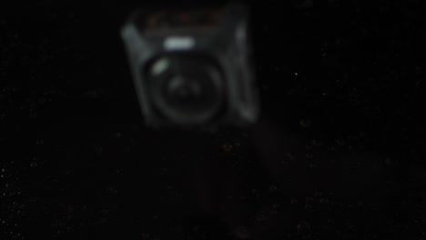 Key mission 360 drops into black water splashing in slow motion