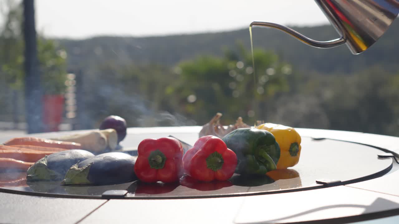 oil being drizzled over vegetables and meats whilst cooking on an open bbq