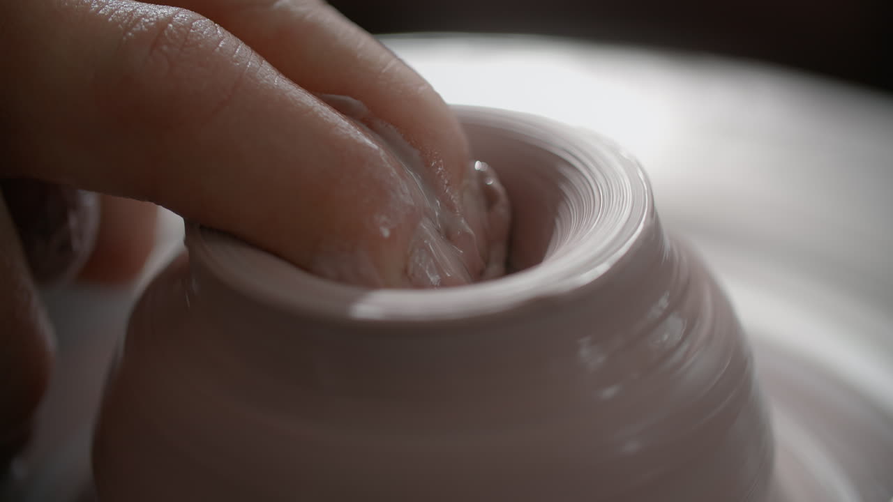 Close-up of a potter's hands shaping clay on a pottery wheel