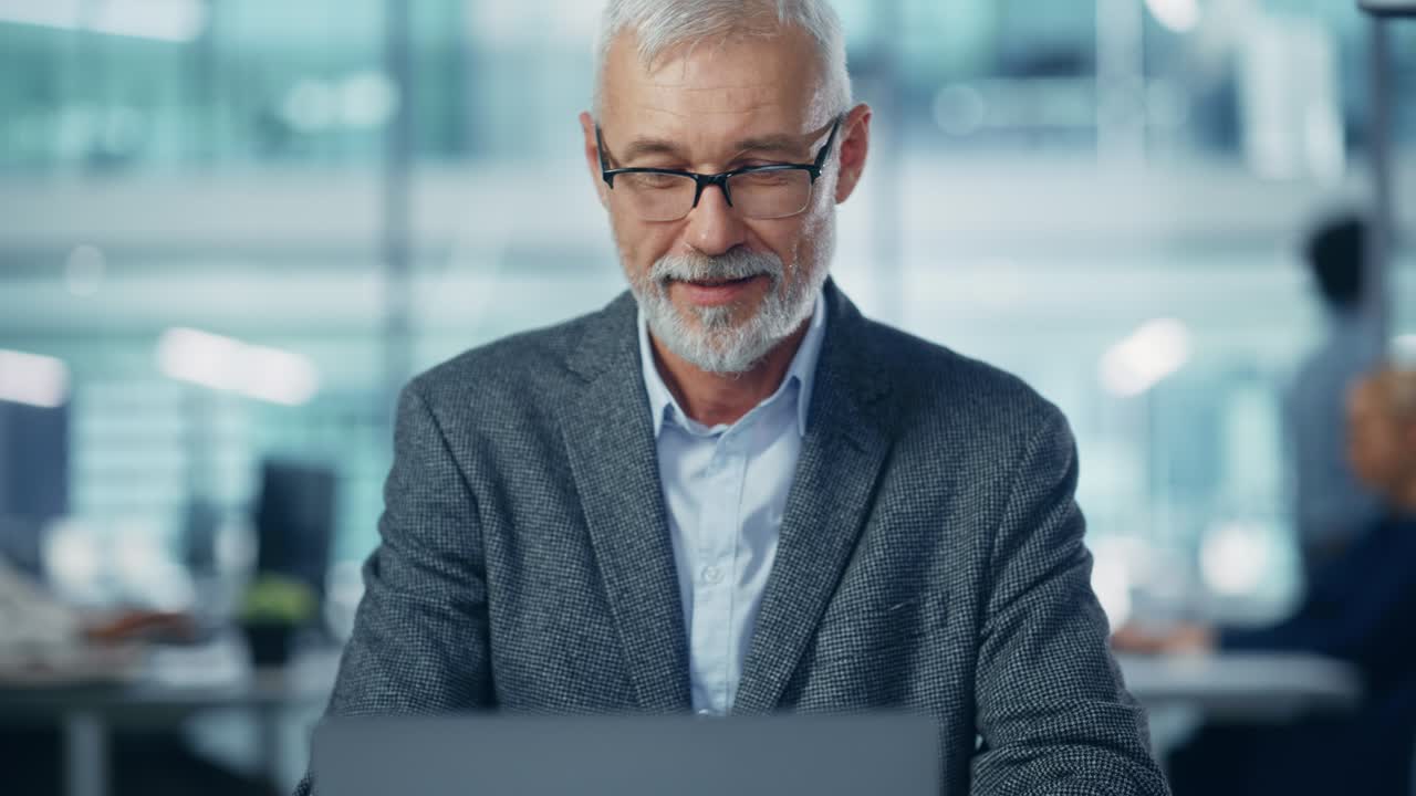 In Office: Portrait of Successful Middle Aged Corporate Businessman Working on Computer at his Desk, Folding Hands in a Gesture of Thinking, Finding Solution, Thoughtfully Contemplating Problem