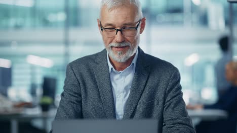 en la oficina: retrato de un exitoso empresario corporativo de mediana edad trabajando en la computadora en su escritorio, cruzando las manos en un gesto de pensar, encontrar una solución, contemplar reflexivamente el problema