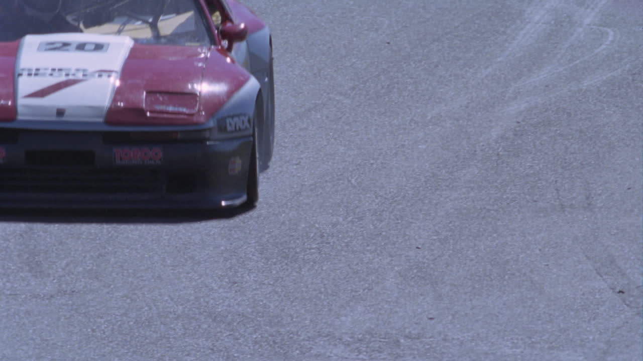 경주용 자동차가 트랙을 속도를 줄이고 회전합니다.