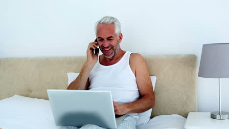 Laughing-man-using-laptop-while-on-the-phone