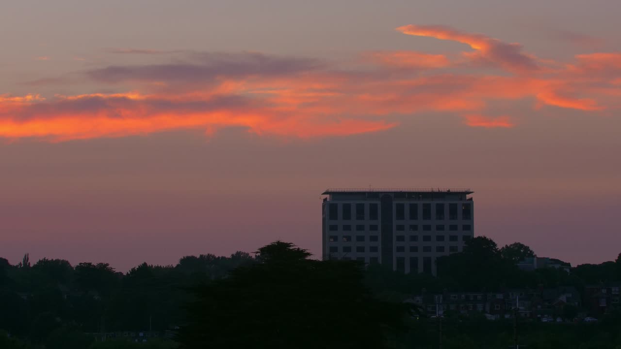 고층 사무실 건물의 넓은 새벽 일출 시간 경과와 전경에 윤곽을 그린 나무