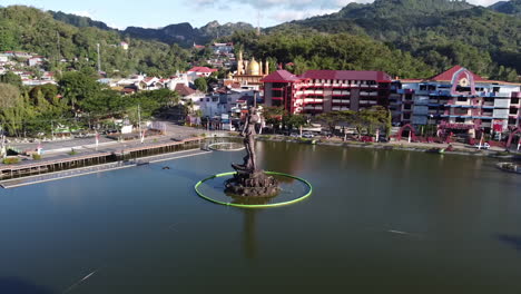 aerial view of a prominent statue in a city lake with mountains in the background