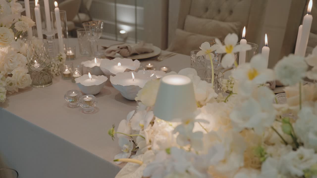 Luxurious wedding table decorated with white flowers, crystal glassware, and soft candlelight