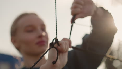 close-up of volleyball net held by someone in green sweater, face slightly blurred, checking it with golden light reflecting around her, creating a warm, focused atmosphere