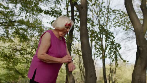 corredora deportiva senior mujer usando reloj inteligente tocando la pantalla táctil, rastreando el resultado. entrenamiento de fitness