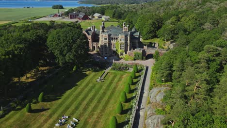 lush green forest surrounds the tjoloholm castle in tjolaholms slott, kungsbacka, sweden. aerial