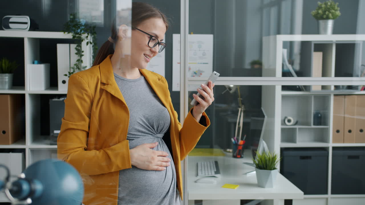 Mulher grávida usando smartphone no escritório