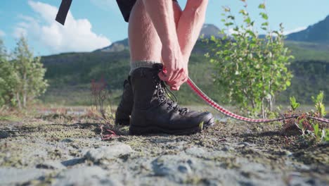 Mann-Beim-Wandern-Im-Ånderdalen-Nationalpark-Auf-Der-Insel-Senja,-Norwegen-Schnürt-Seine-Stiefel-Auf,-Um-Sich-Zu-Entspannen