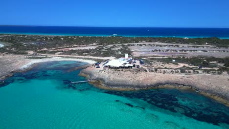 sailboats anchored in turquoise waters near a beach restaurant on the idyllic island formentera, spain. lovely aerial view flight