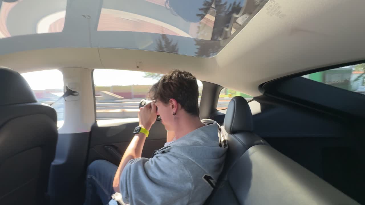 Persona sentada en el asiento trasero de un Tesla Model 3