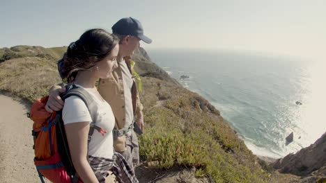 father and daughter hiking at mountain top, standing on cliff and enjoying view of sea