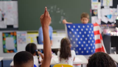 rear view of schoolboy raising hand in the classroom 4k