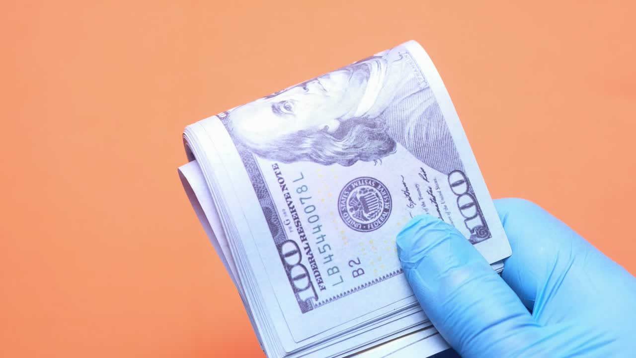 의료 장갑에 담긴 미국 달러 한 어리