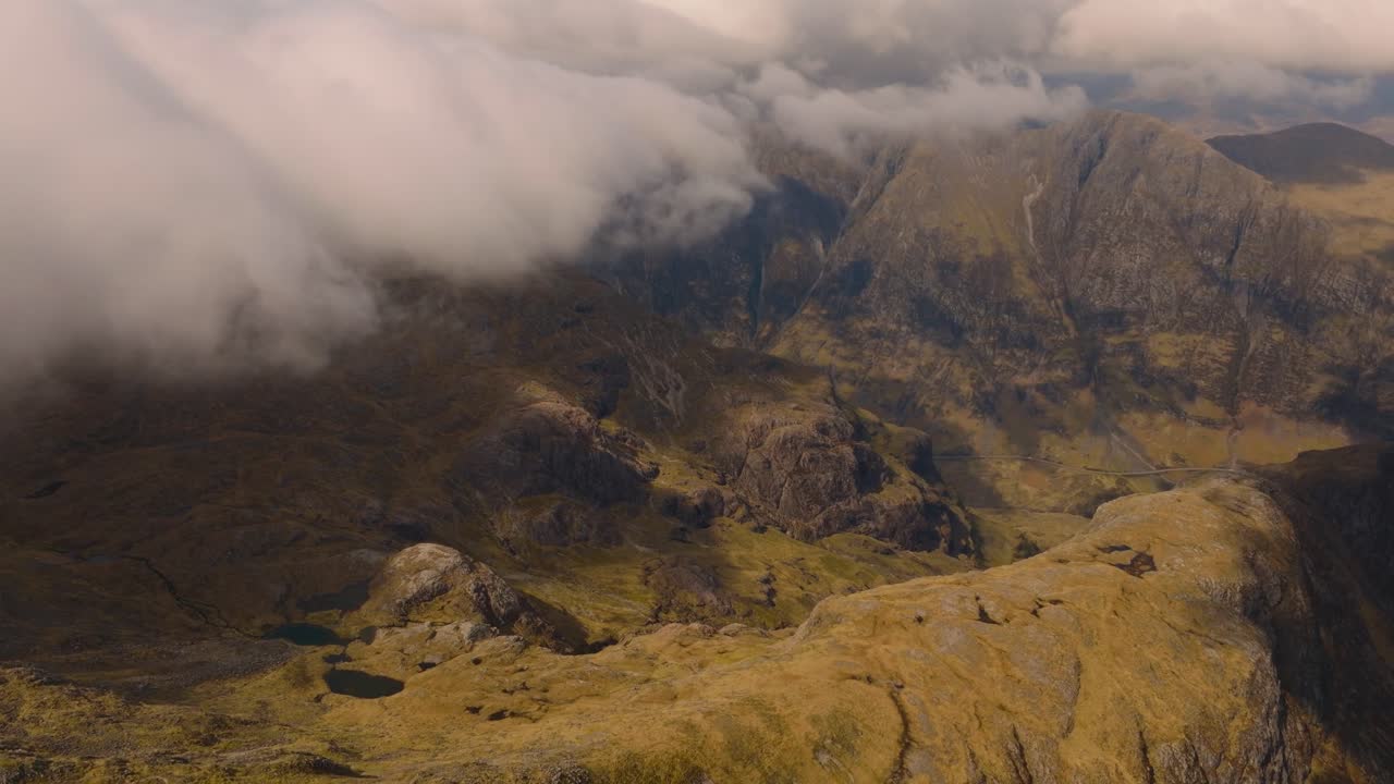 Aerial drone footage of Bidean Nam Bian, the highest mountain in Glencoe, Scotland, covered in snow. Sweeping views of snowy peaks, deep valleys, and dramatic Highland scenery