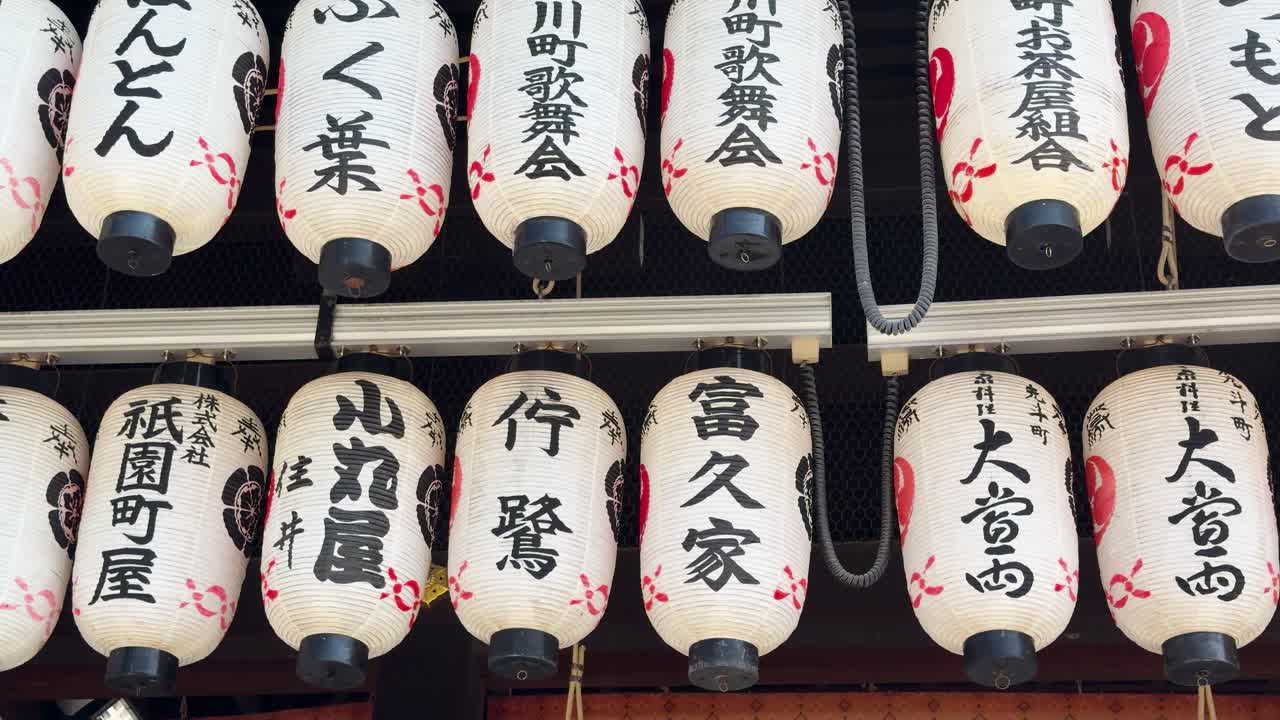 File di lanterne di carta bianche con calligrafia kanji nera pendono in un santuario di Kyoto.