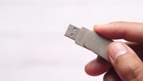 hand holding a silver usb flash drive