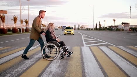 man helping woman in wheelchair across street