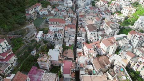 Una-Toma-Aérea-Moviéndose-Lentamente-Sobre-Los-Tejados-Rústicos-De-Pizarra-Y-La-Estrecha-Carretera-Central-En-La-Histórica-Ciudad-De-Amalfi,-Uno-De-Los-Destinos-Turísticos-Más-Populares-En-La-Famosa-Costa-De-Amalfi-En-Italia