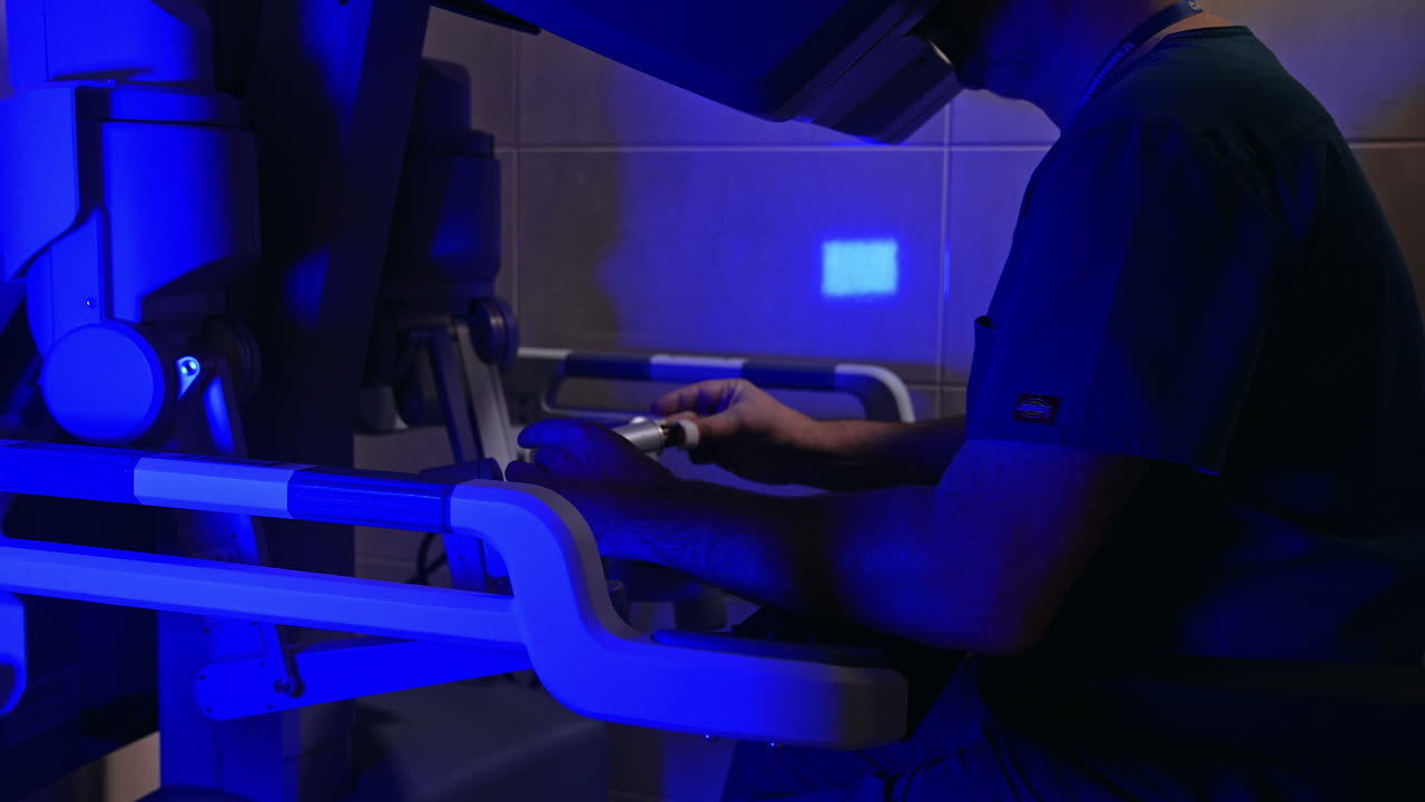 Experienced male surgeon works on innovative robotic equipment. Doctor leaves the handles continuing to look at binoculars.