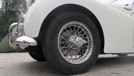 close-up of a white vintage car's wire wheel and fender