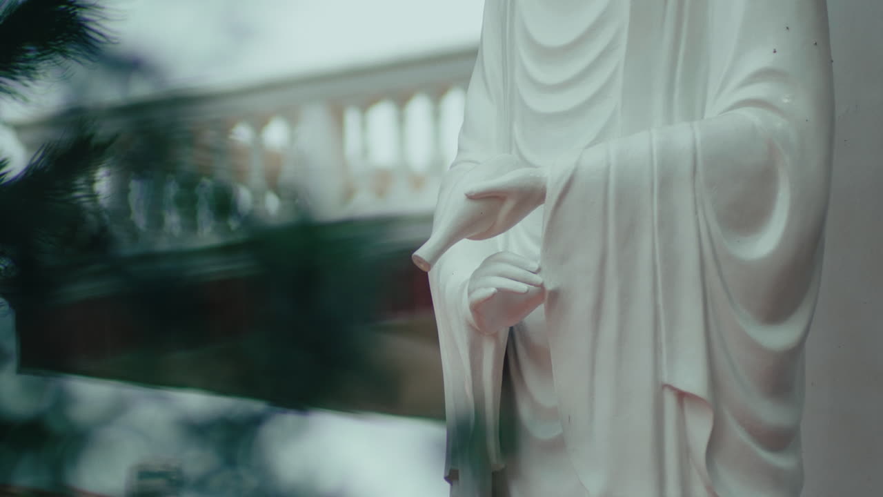 Close-up of the Buddha statue holding a jar, with bokeh in the background