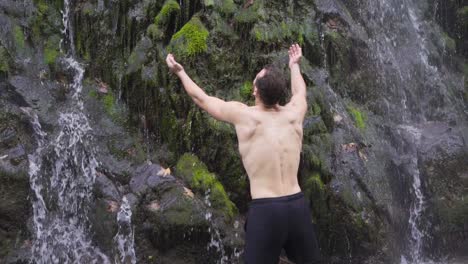 muscular male in front of waterfall, happy. slow motion.