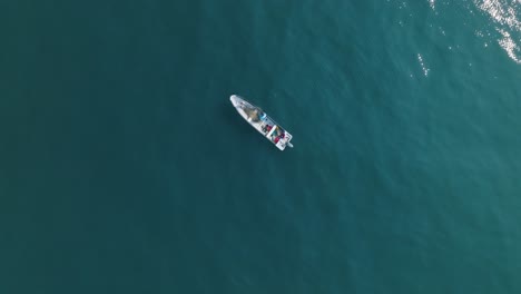 vista aérea de arriba hacia abajo en cámara lenta de un pequeño barco de pesca en el tunco el salvador