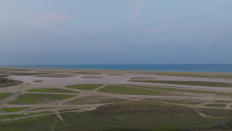 fotografía aérea de los humedales costeros al crepúsculo con patrones en la arena y el mar