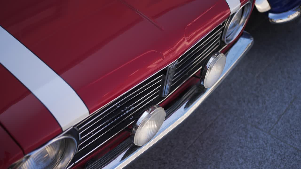 Front view of a red vintage car with chrome details and white racing stripes
