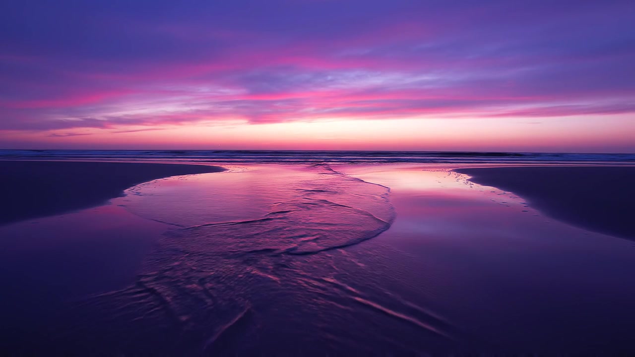 Splendido tramonto viola e rosa su riflessi calmi della spiaggia