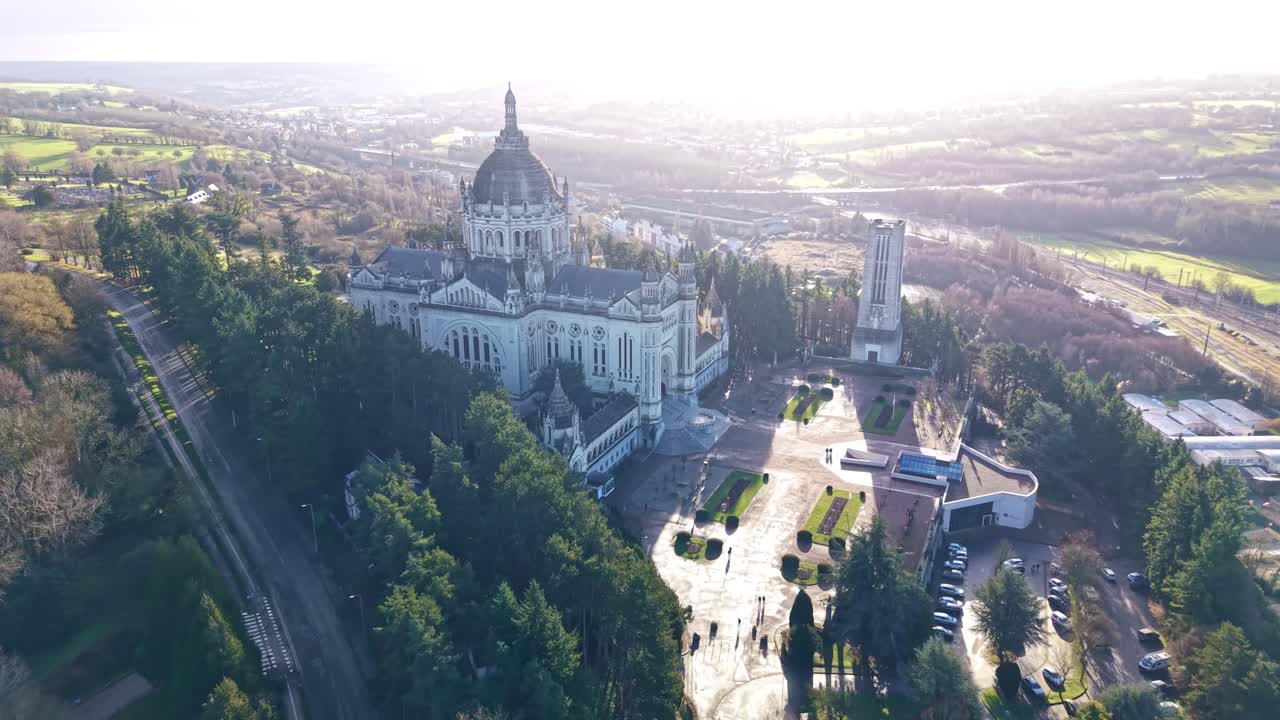 Drone, der trækkes ud fra Basilique Sainte-Thérèse de Lisieux i Lisieux, Calvados, Normandiet, Frankrig, og afslører Esplanade Sainte-Thérèse, Jardin du Carmel-parken og den omkringliggende by og landskab