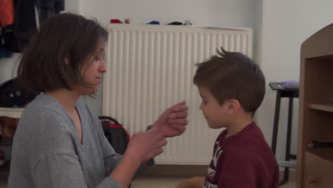 caucasian is been cared of her little boy indoors by fixing her hair